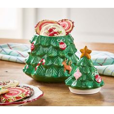 two ceramic christmas trees sitting on top of a table next to plates and napkins