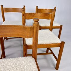 three wooden chairs sitting next to each other on top of a white carpeted floor