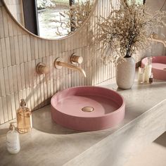 a bathroom with two sinks and a round mirror on the wall next to each other