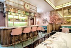 the interior of a restaurant with tables, chairs and a clock on the wall above the bar