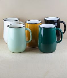 four different colored coffee mugs sitting on a table