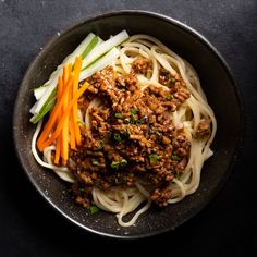 a bowl filled with noodles and meat next to chopsticks on top of a table