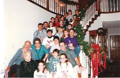 a large group of people are posing for a photo in front of the christmas tree