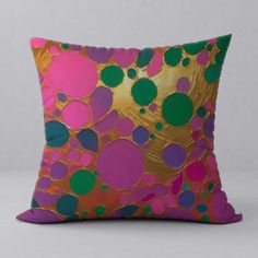 a pink and green pillow sitting on top of a white floor next to a wall