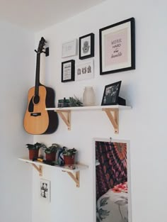 a guitar is hanging on the wall next to some shelves with pictures and other items