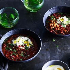 three bowls filled with different types of food on top of a black table next to drinks