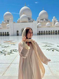 a woman standing in front of a white building with domes on it's sides