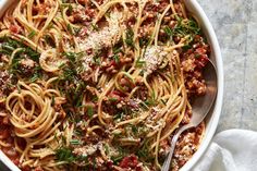 a white bowl filled with pasta and meat topped with parmesan cheese on top