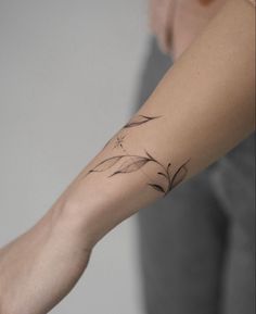 a woman's arm with a tattoo on it that has flowers and leaves on it