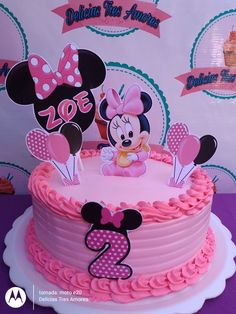 a minnie mouse cake with pink frosting and decorations