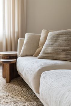 a white couch with pillows on it in front of a coffee table and window sill