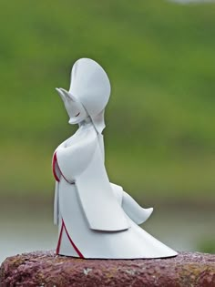 a white figurine sitting on top of a rock