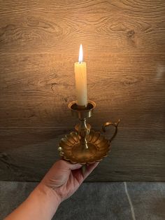 a person holding a lit candle in front of a wood paneled wall and ceiling