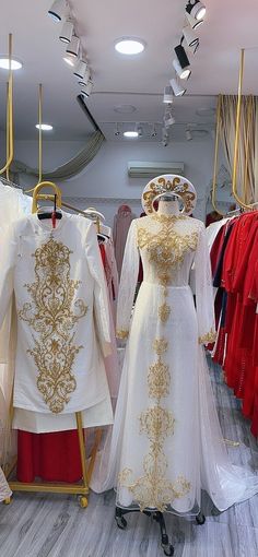 two mannequins dressed in white and gold gowns, one wearing a tiara