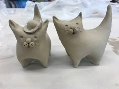 two ceramic cats sitting next to each other on a table