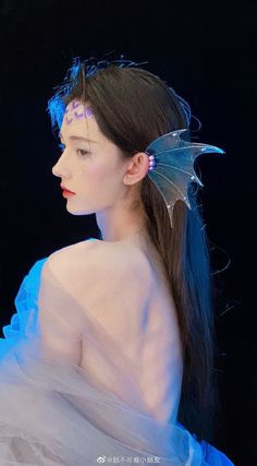 a woman in a blue dress with a dragon wing on her head and long hair