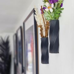 two vases with flowers are hanging on the wall