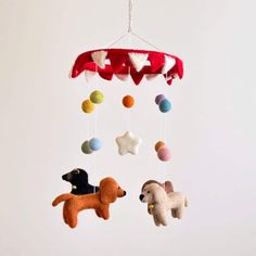 a mobile with three dogs hanging from it's sides and two balls in the shape of stars