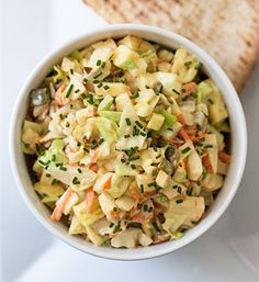 a white bowl filled with salad next to pita bread