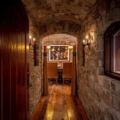 an archway leading to a dining room with stone walls and wood flooring is lit by candles