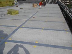 two people standing on the side of a train track with their shadows on the ground