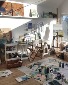 an artist's studio with many paintings on the floor