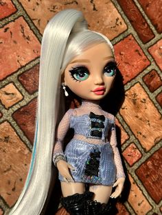 a doll with long white hair and blue eyes is standing on a tile floor next to a brick wall