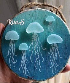 a person holding up a piece of wood with jellyfish on it and the words kios written in white