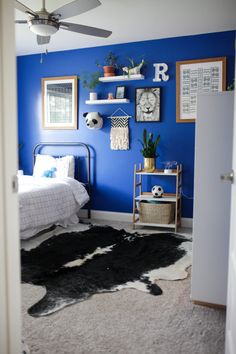 a bedroom with blue walls and black and white cow skin rugs on the floor