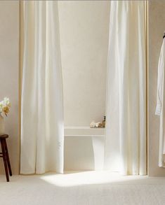 a white bath tub sitting next to a window covered in curtained drapes