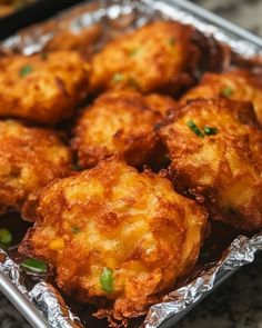 some fried food is sitting in a tin foil pan on the counter top and ready to be eaten