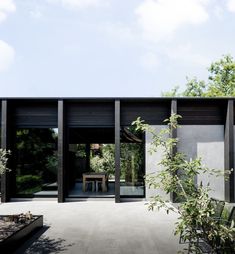 an outdoor area with black walls and wooden furniture on the outside, surrounded by greenery