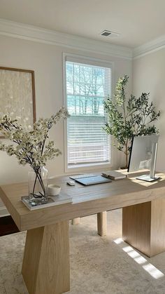 two vases with flowers are sitting on a table in front of a large window