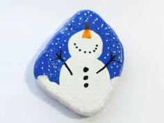 a painted rock with a snowman on it's face and an orange hat