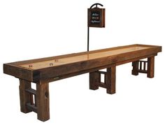 a long wooden table with two benches underneath it and a sign on the back side