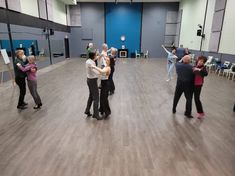 a group of people standing on top of a wooden floor next to each other in a room