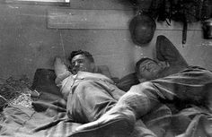 an old black and white photo of two men laying in bed