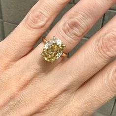 a woman's hand with a yellow and white diamond ring on top of her finger