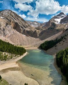 the mountains are covered in snow and green trees, with a small lake below them