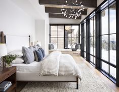 a bedroom with a large bed and lots of windows on the side of the room