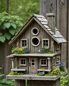 a bird house with flowers and birds in the window boxes on it's roof