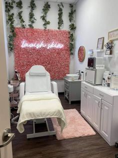 a room with white furniture and pink flowers on the wall, along with a neon sign that says love is in bloom