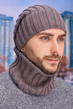 a man wearing a knitted hat and sweater in front of a cityscape