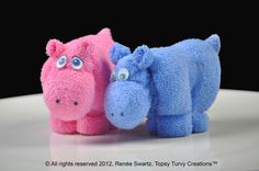 two stuffed hippos sitting next to each other on top of a white table