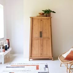 a tall wooden cabinet sitting next to a white wall in a room with a rug on the floor