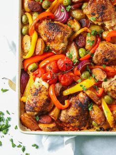 a casserole dish filled with chicken, peppers and onions on a white surface