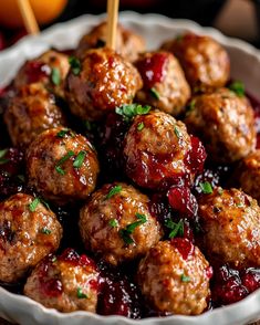 a white bowl filled with meatballs covered in cranberry sauce