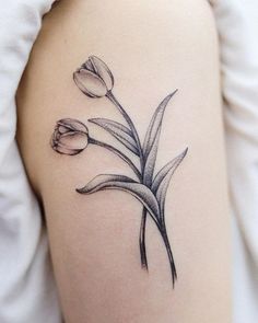 a black and white photo of a flower on the back of a woman's arm