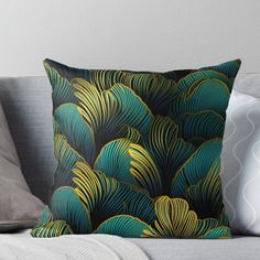 a green and gold throw pillow sitting on top of a gray couch next to pillows