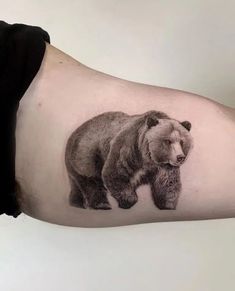 a black and white bear tattoo on the left arm, with an inked image of it's cub